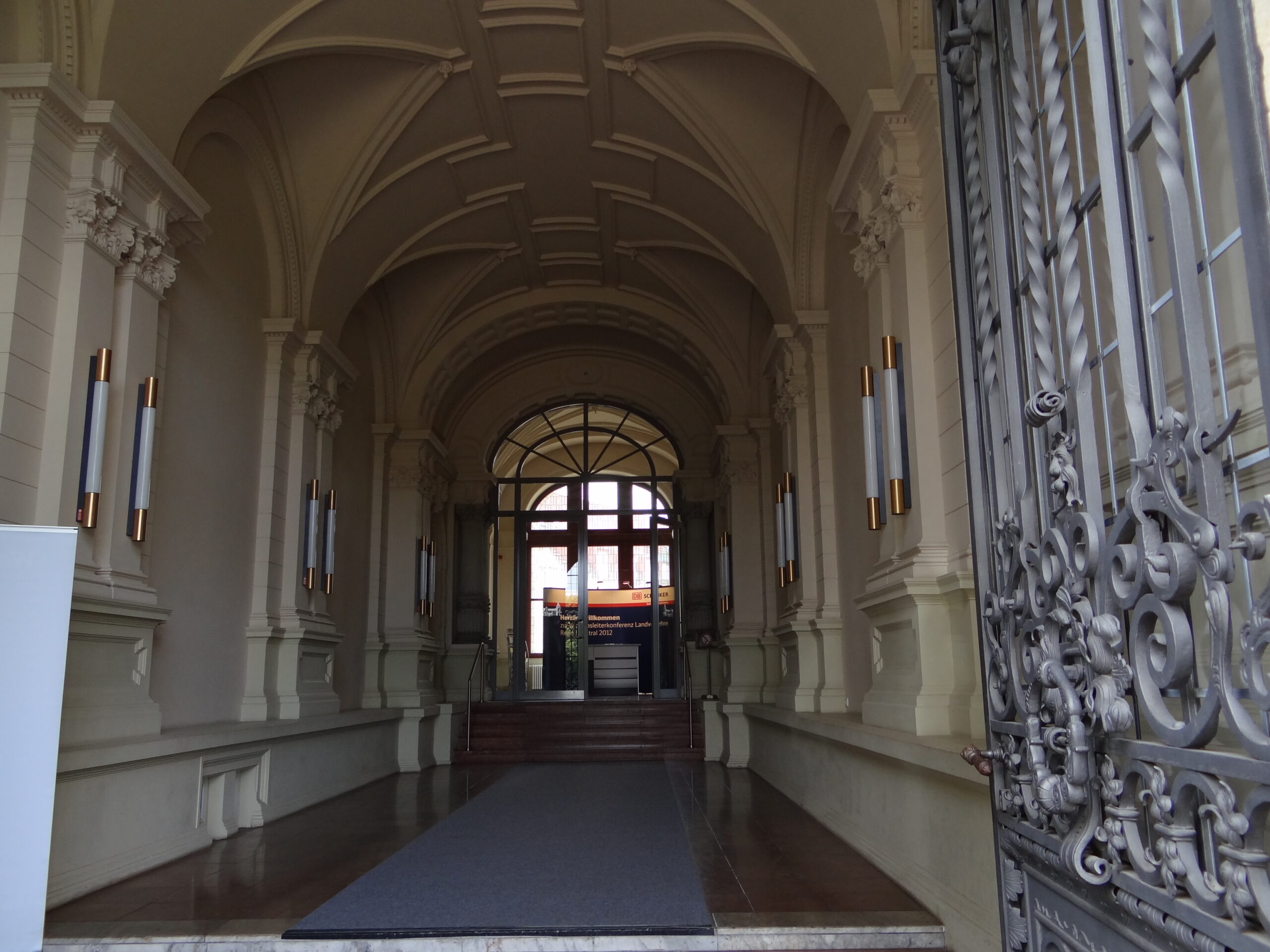 Blick durch das schmiedeeiserne Tor in die gewölbte Eingangshalle.