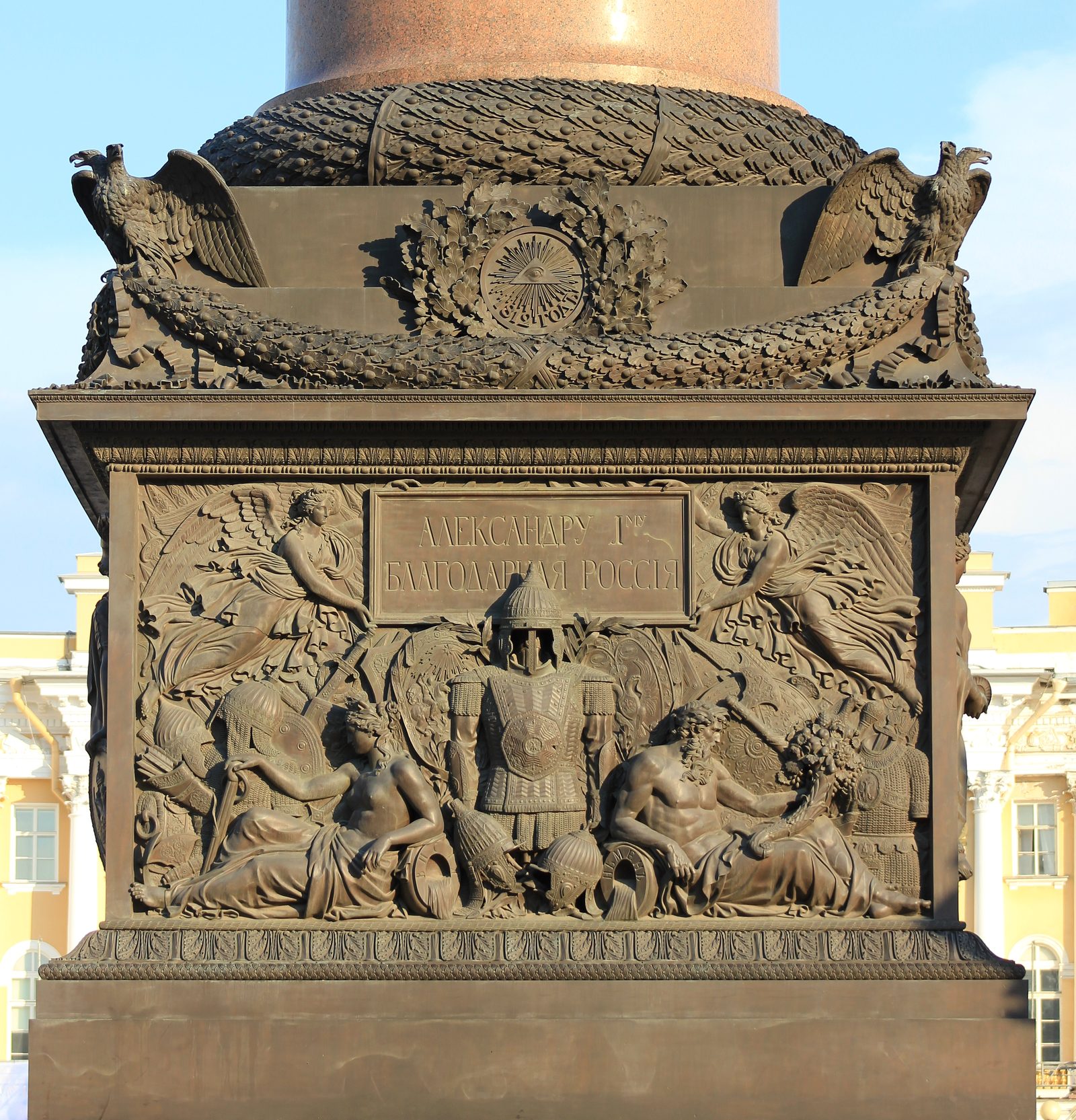 Sockel der Alexandersäule mit Bronzereliefs, oben über der Girlande das Auge im Strahlenkranz, darunter Waffen und Figuren