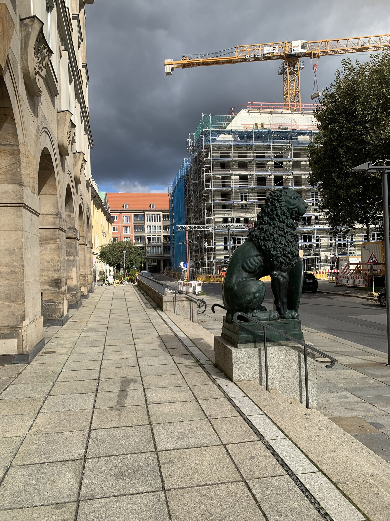 Arkade des Neuen Rathauses in Dresden mit Bronzelöwe, gegenüber ein eingerüsteter Neubau, 2024.
